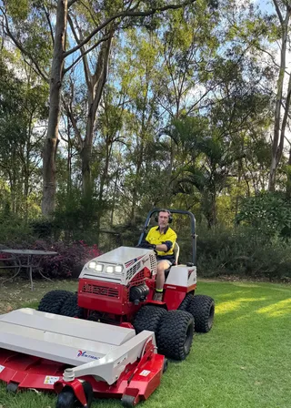 Andrew on the Ventrac 4520P with the finish mower, on a lawn under eucalypts, Pullenvale